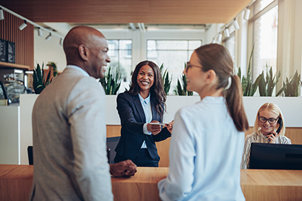 Smiling concierge helping two guests check in to a hotel